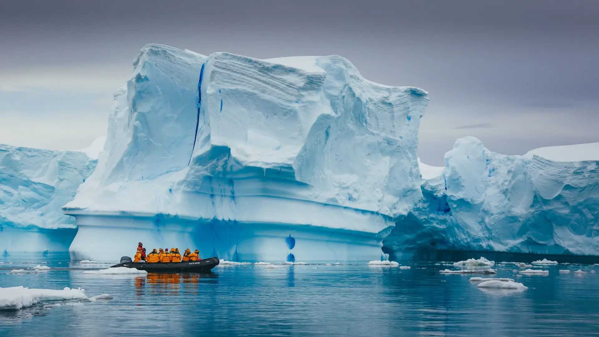 Delegates in an expedition boat beside an Antarctic iceberg
